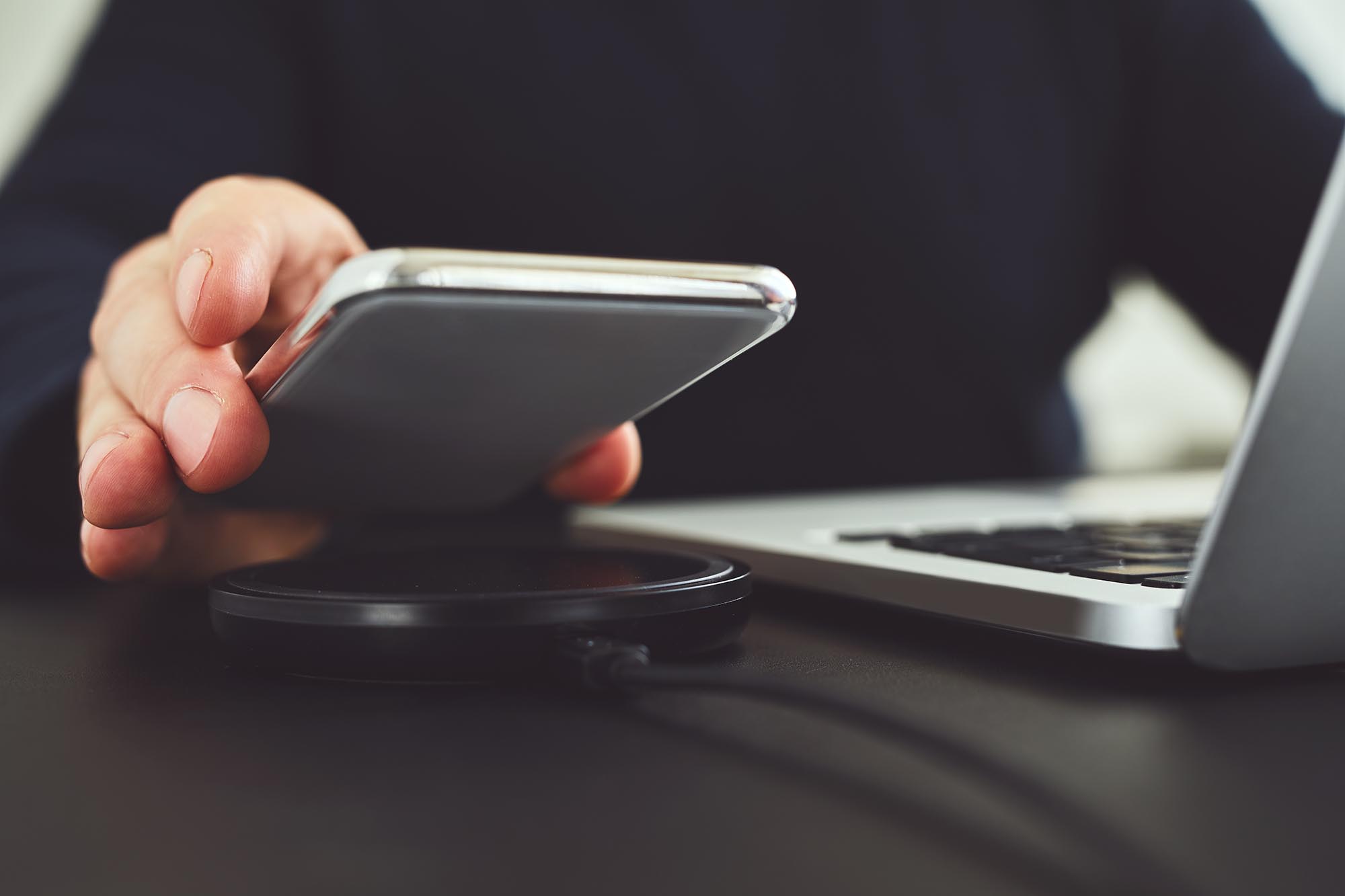 Man puts mobile phone on wireless charger on table